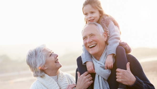 Grandparents on a beach carrying their young granddaughter on their shoulders | Estate Tax Planning Top of Mind Going into Election Day | Income Tax Planning Services in Columbus Ohio | Estate Tax Planning Services in Columbus Ohio | Blue and Co. LLC